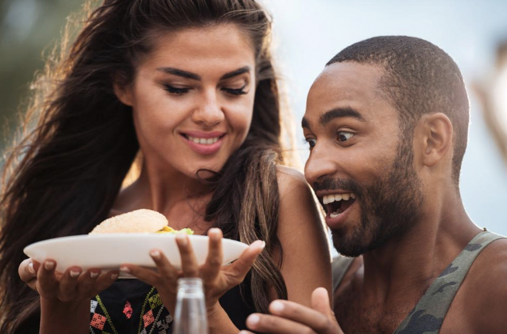 Happy Man and Woman Smiling Over a Sandwich